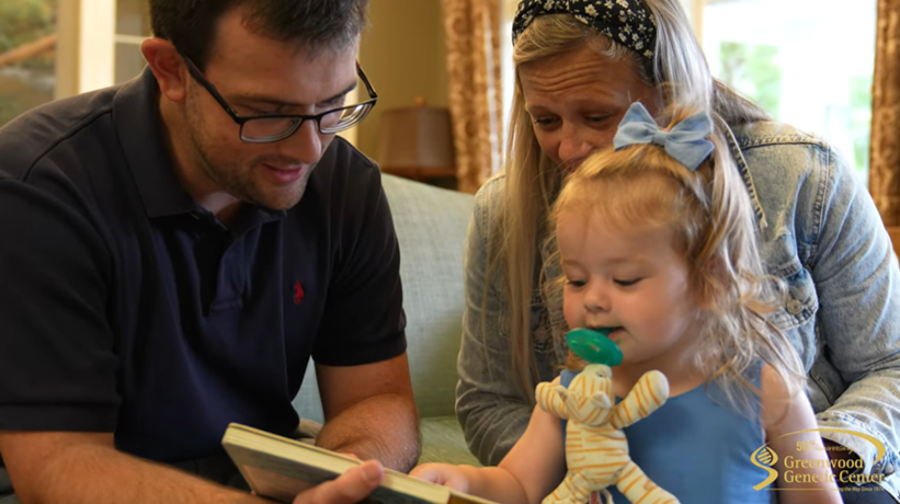Toddler looking at a book with her parents