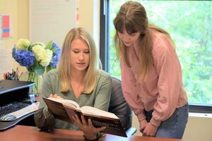 Genetic assitant and genetic counselor look at a book