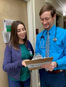 Two physician assistants with a clipboard talking